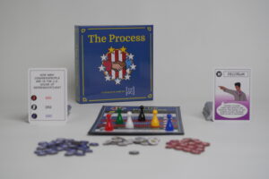 A complete set of The Process Game with all its components (political and trivia cards, gamr board, game pieces, and tokens) laid out.